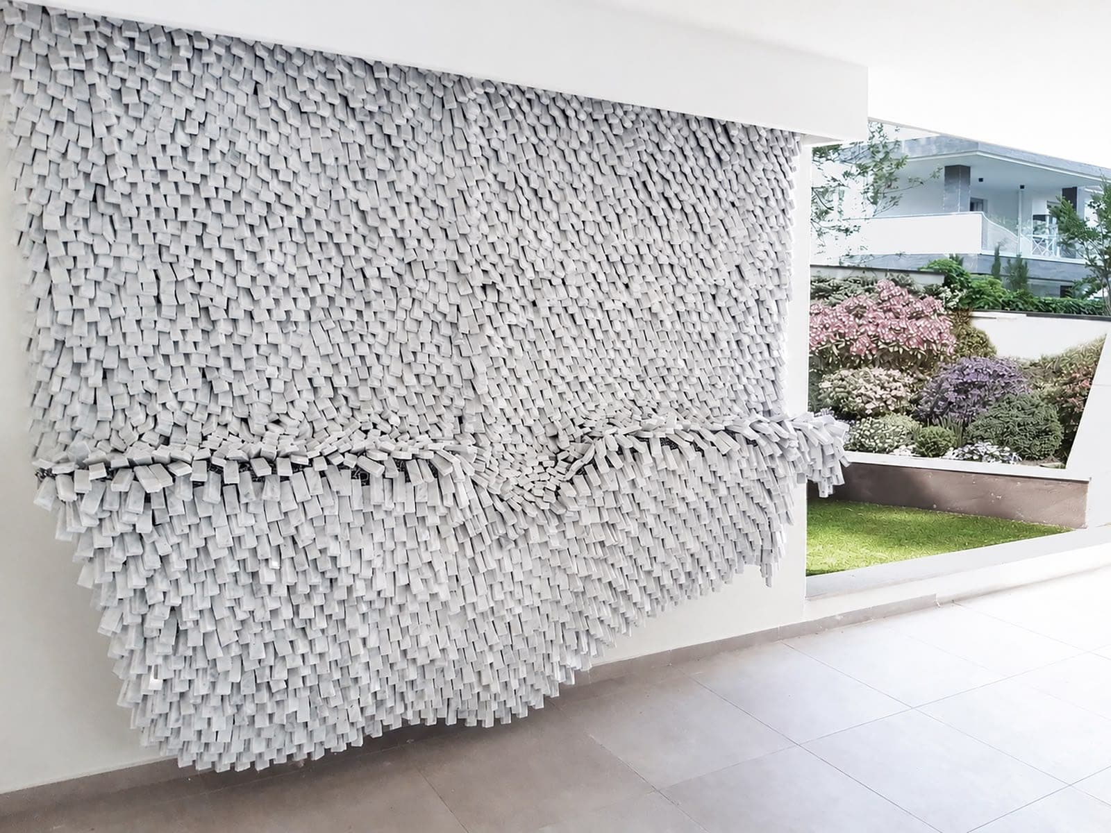 Rigid fragments made to fall like cloth: a wall of marble.