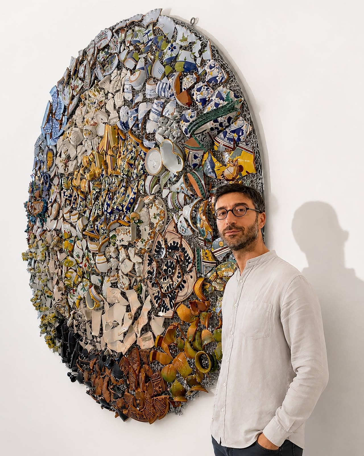 The artist beside a circular composition of salvaged ceramic.