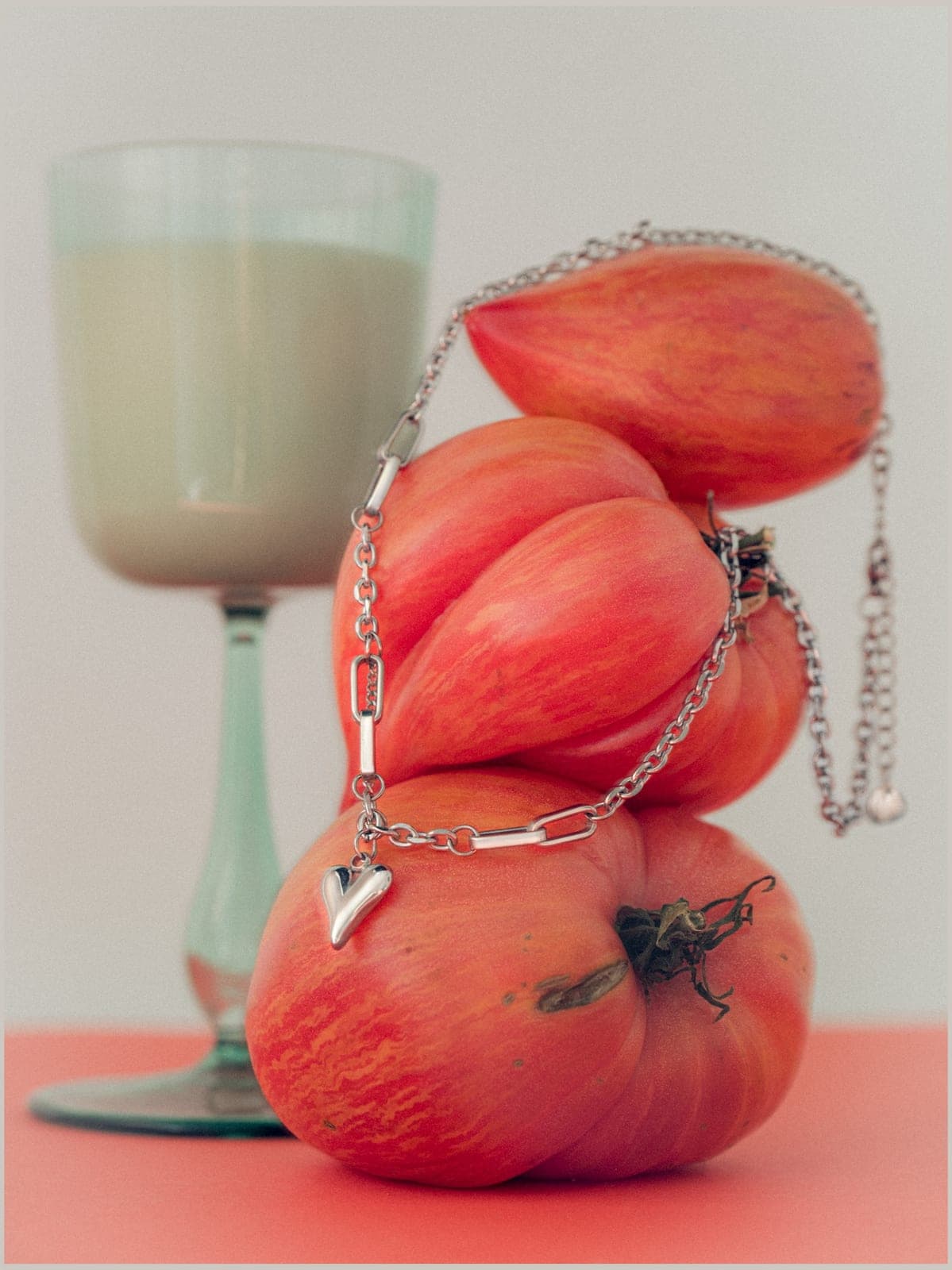 A silver chain draped over heirloom tomatoes.