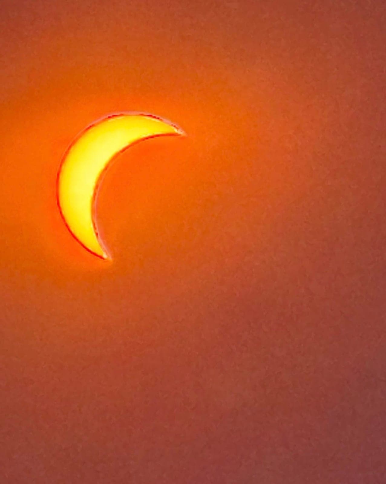 A crescent sun, burning orange.